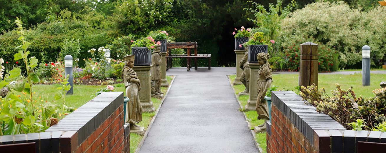 The walkways are lined with beautiful ceramic statues and planters. At the end of the walkway a bench with views of the garden is placed, before leading into a wooded area or breaking off towards the flourishing gardens.