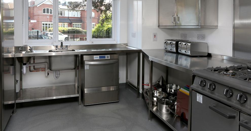 State of the art industrial styled kitchen, featuring all stainless steel appliances and a grey resin floor creating a monochrome look.