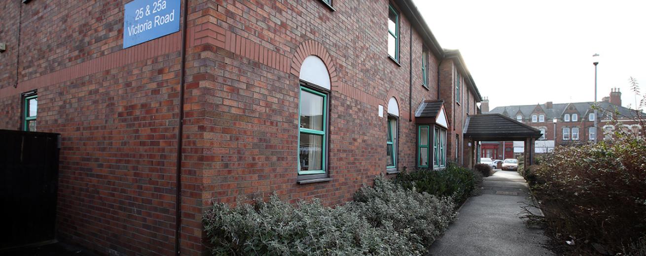 Sizable property featuring mint green framed windows and white blocked shapes fitting perfectly into the built in brick features. The landscaping perfectly frames the walkways around the properties.