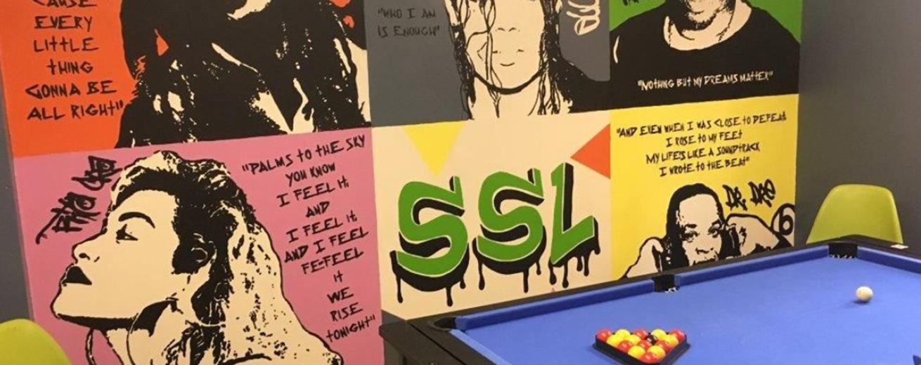 Bold graffiti style wall art is the main feature of the room which also hosts a black and blue, set up pool table.