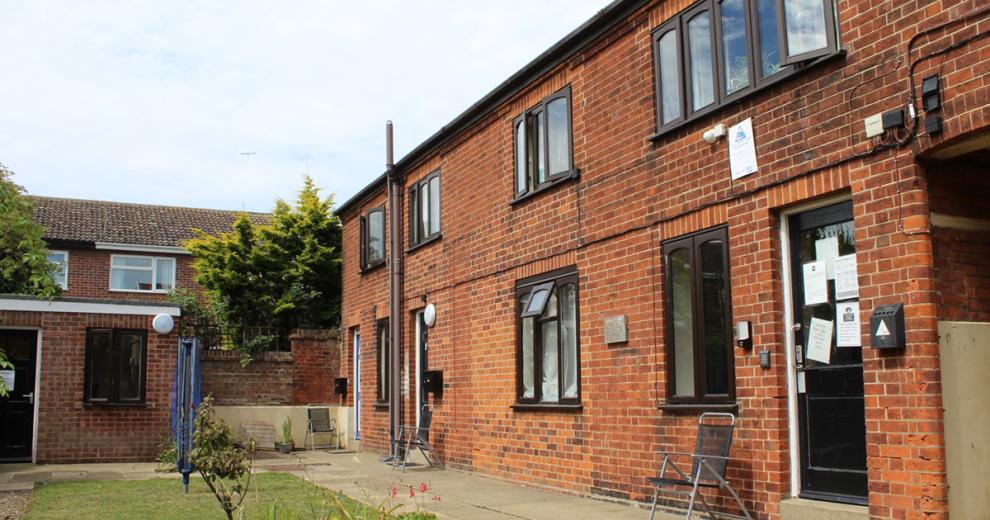 Compact Garden area with scattered seating, a brick-built garage and area to dry washing.