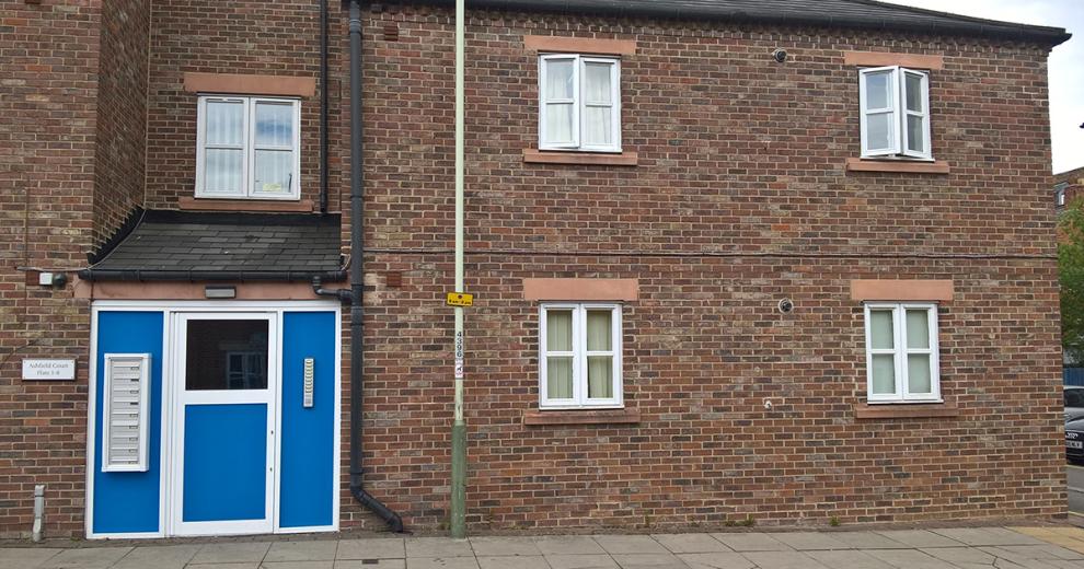 Two storey brick property at Ashfield Court, with vibrant blue and white secure door access.