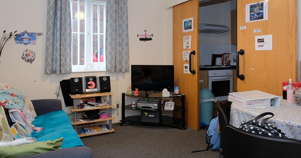 Cosy communal seating area, with access to a sofa, small television and dining room table. Sliding doors lead through into the kitchen area.