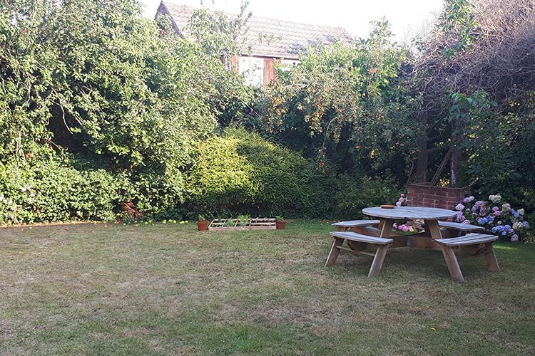Calming garden space with large hedging and circular bench seating.