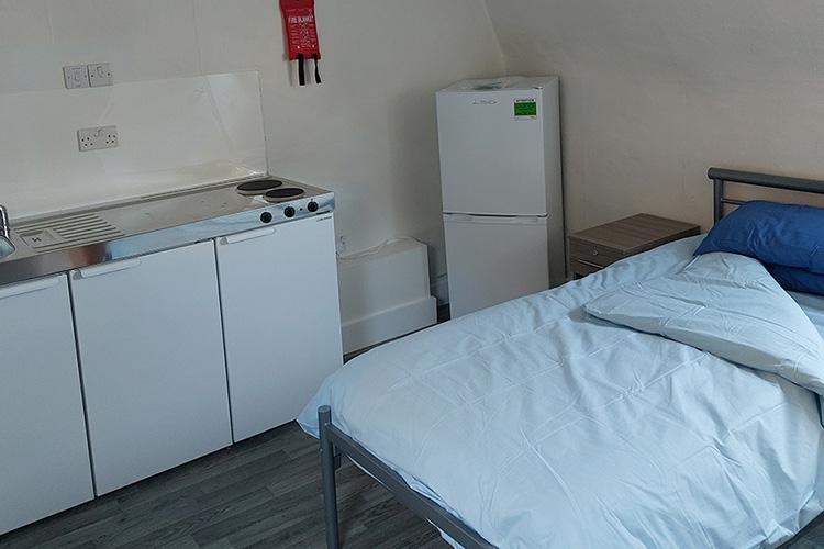 Single bedded studio flat, including a two-burner hob, sink, trio of cupboards and fridge freezer.