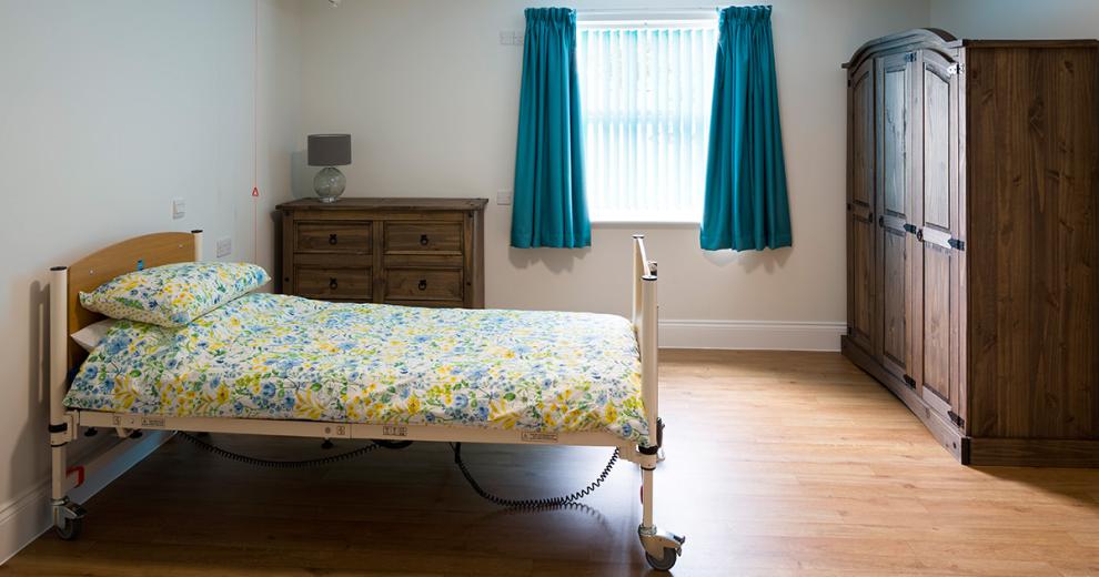 Substantial sized resident room. Featuring a three-door oak wardrobe with matching six draw chest of draws and a comfortable medical bed.