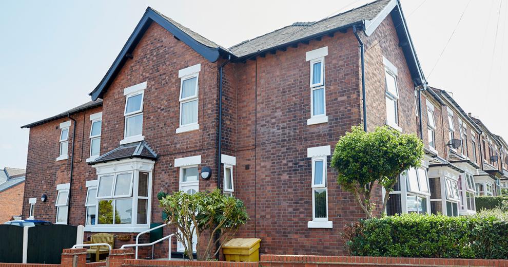 Characteristic, weathered dark brick residential home, with accessible entry to the care facility.