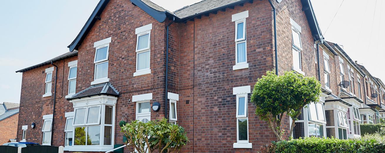 Characteristic, weathered dark brick residential home, with accessible entry to the care facility.