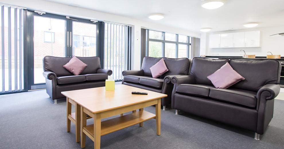 Spacious open plan seating area following through from the kitchen diner. Consisting of three homey sofas with large central coffee table and double French doors leading to an outdoor area.
