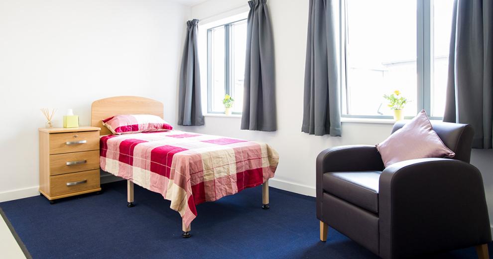 Bright and cosy single bed, room with chest of draw bed side table and a single person seating area in front of two good sized windows.