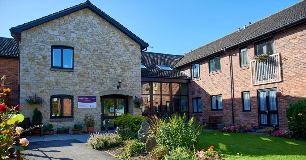 A stunning blend of stone materials for the façade of the entrance to Harry Garrett Court, the dark wooden framed window and doors contrast beautifully, to the left there is a wonderful floor to ceiling walkway linking to the traditional red brick extension. The well maintained gardens guide you to the entranceway in an inviting manner.