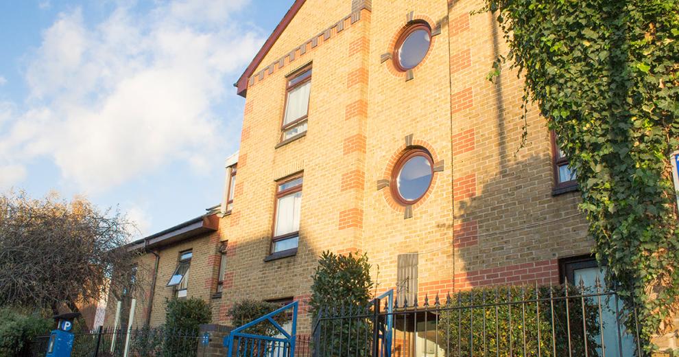 Yellow bricked multi storey supported housing property at John Pounds House in Wandsworth. With a focal feature of circular windows above the entry way.