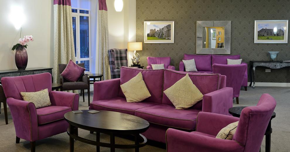 The multiple purple sofas and arm chairs are the main focus point of the room adding vivid colour. The perimeter of the room are dress with ornate tables with elaborate vases.