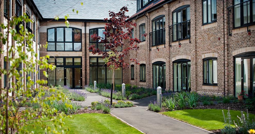 The garden walkways to and from the property create a serene space, with light beacons lighting the tarmacked walkways. Mature lavender plants and shrubbery lining the perimeter as well as young trees planted in full view for the second storey residents.