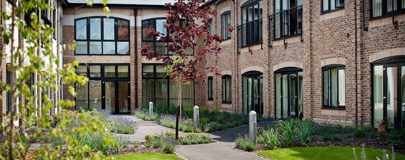The garden walkways to and from the property create a serene space, with light beacons lighting the tarmacked walkways. Mature lavender plants and shrubbery lining the perimeter as well as young trees planted in full view for the second storey residents.