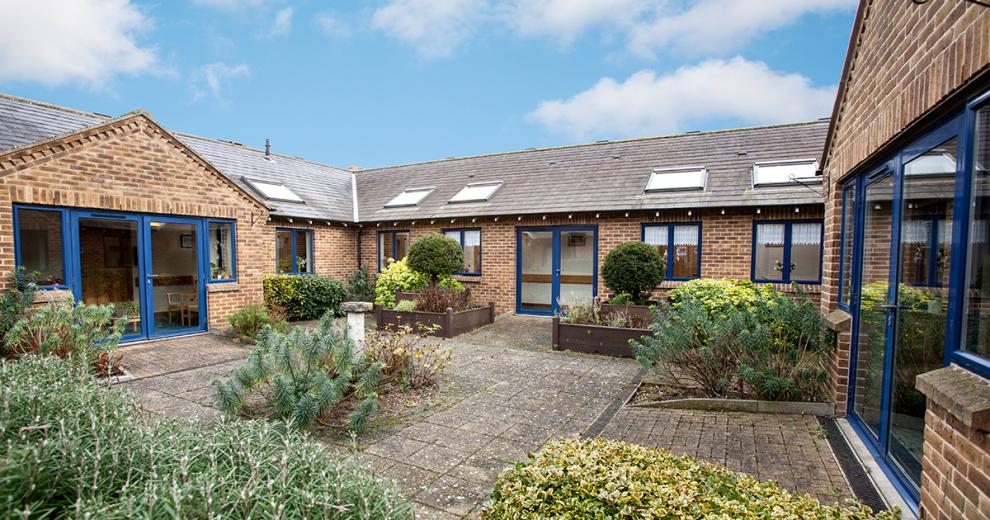 A single storey property, with a small but flourishing courtyard area. The building is built in a 50’s style brown brick built style. The framing for the doors and windows are all in a royal blue adding a pop of colour to the outside area. Skylights have been placed all along the roof.