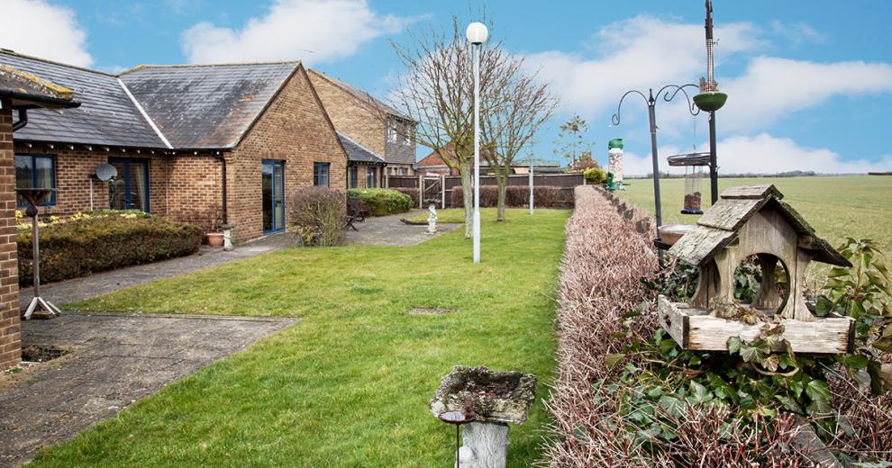 A petite garden area that spans the length of the property, is made up of a paved access all around the perimeter of the building then onto the grassed area. A waist height hedge marks the boundary of the property but allows views onto the neighbouring field.