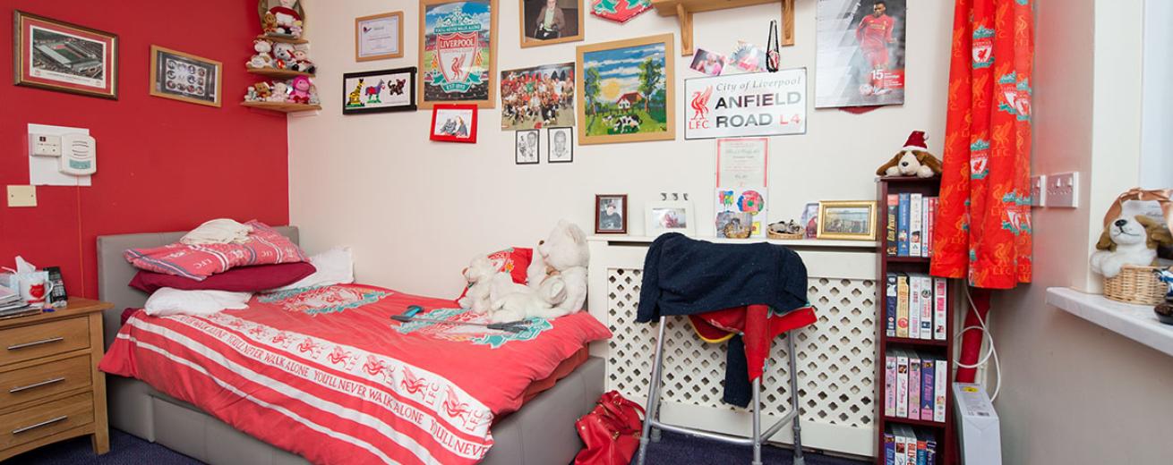 Large single bed room. Decorated in red and white painted walls, a single bed tucked into the corner and the room dress in Liverpool FC memorabilia.