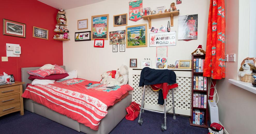 Large single bed room. Decorated in red and white painted walls, a single bed tucked into the corner and the room dress in Liverpool FC memorabilia.