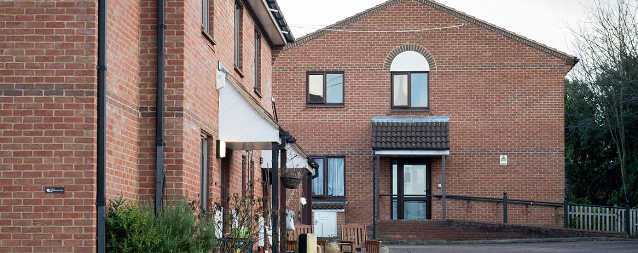 Single storey brick built residential care home, built on a corner plot with outdoor wooden dining set.