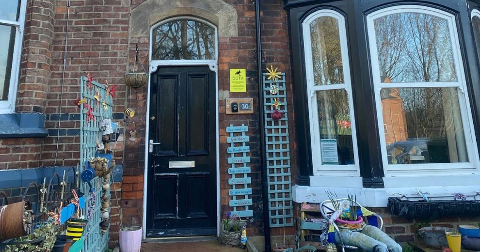 A very homely array of items adorn the outside of the Victorian styled property. Teal blue painted wall trellising and personalised plaques are placed around the doorway and as a separation between the neighbouring property.