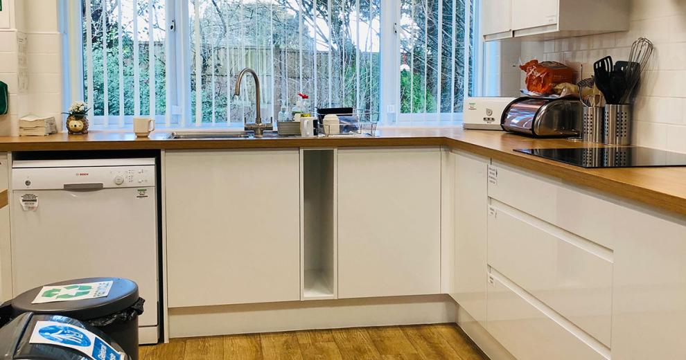 Whitewashed kitchen cabinetry, blending seamlessly into the white kitchen. With industrial style electric hob.