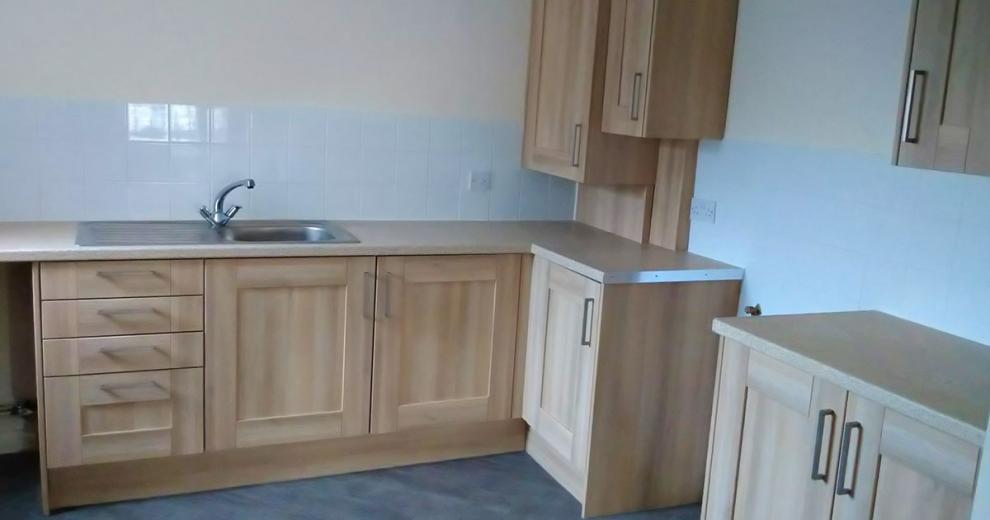 Gorgeous wood panelled kitchen cabinets a slightly lighter wooden flooring, finished with a soft marble effect worktop.