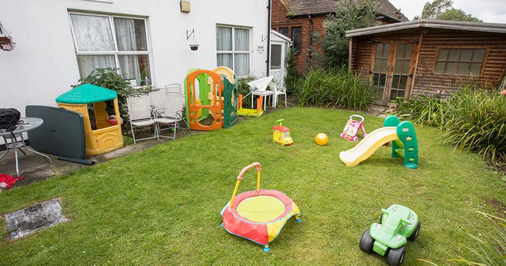 Well maintained grassed garden with a mass amount of children's toys.