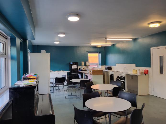 Interior of communal area at Victoria house with blue walls, tables and chairs and a piano.