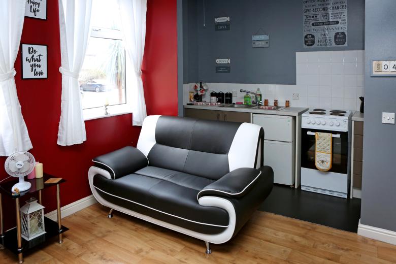 Living area at Victoria House. A black and white sofa in front or red and grey walls