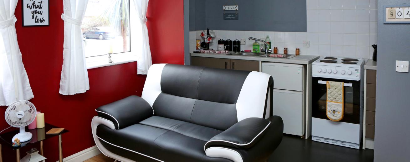 Living area at Victoria House. A black and white sofa in front or red and grey walls