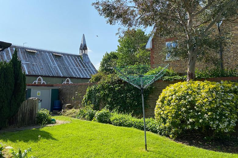 A compact grassed garden area with mature shrubbery lined around the edge creating privacy for the property. The views of the ornate church can be seen to the back of the garden.