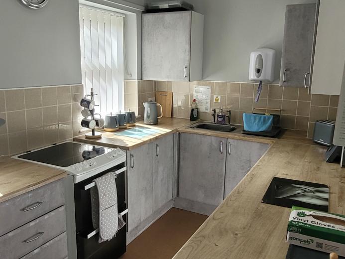 Neutral toned kitchen with grey cabinets and a wooden finish and kitchen utensils on display