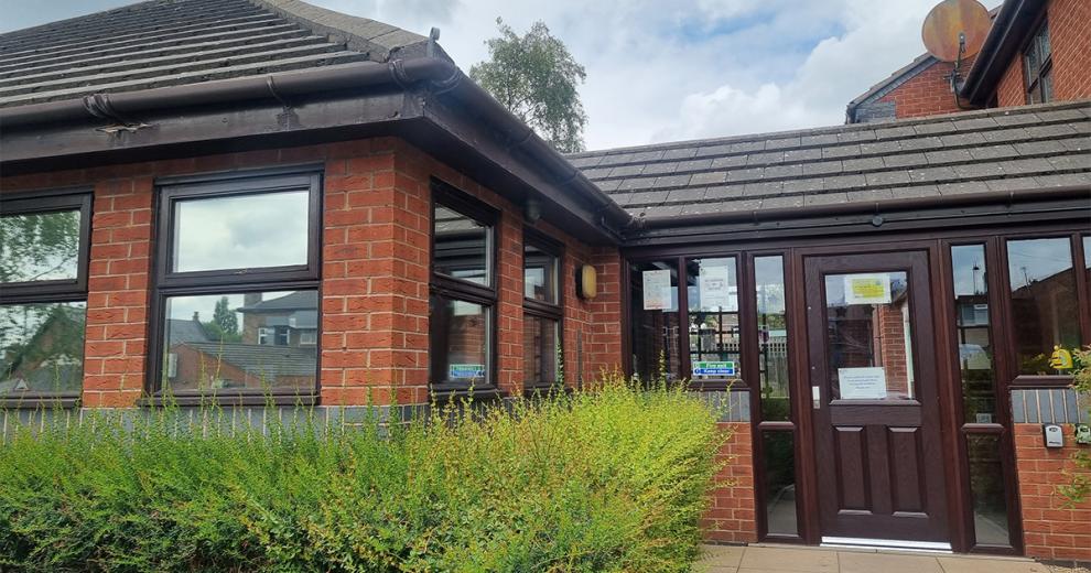 A single storey tradional red bricked building with dark brown window frames and secure entry to the property. Maintained healthy shrubbery has been grown around the perimeter of the building creating a more inviting walkway to the property as well as privacy for residents.