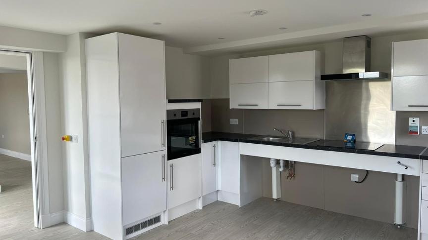 Spacious, furnished bedroom, with window seated armchair and accessibility to an outdoor area.