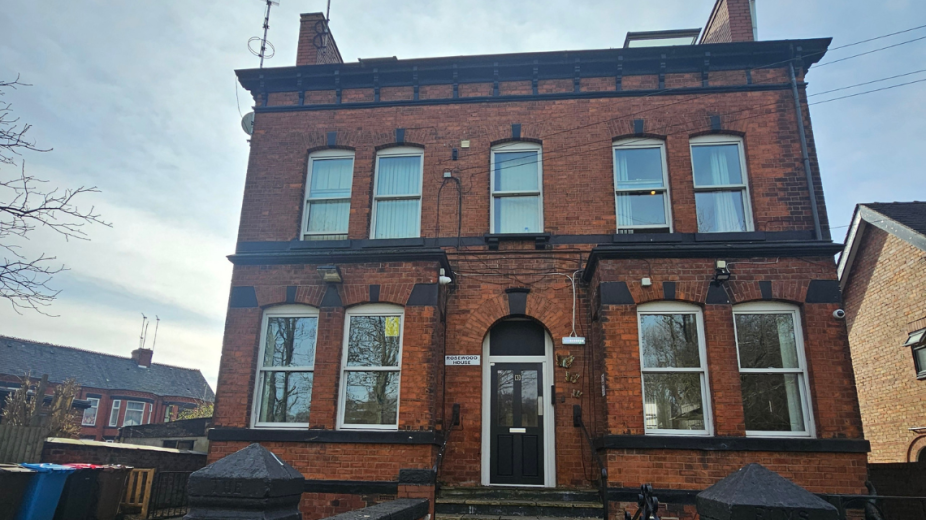 Majestic well weathered brick building, with perfectly symmetrical exterior features including chimneys and windows. As well as a central stepped entry to the front door.