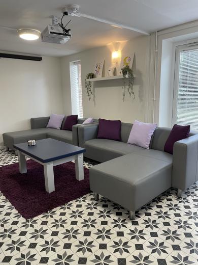 Elongated purple and lime green sofas placed around checked multicoloured rug.