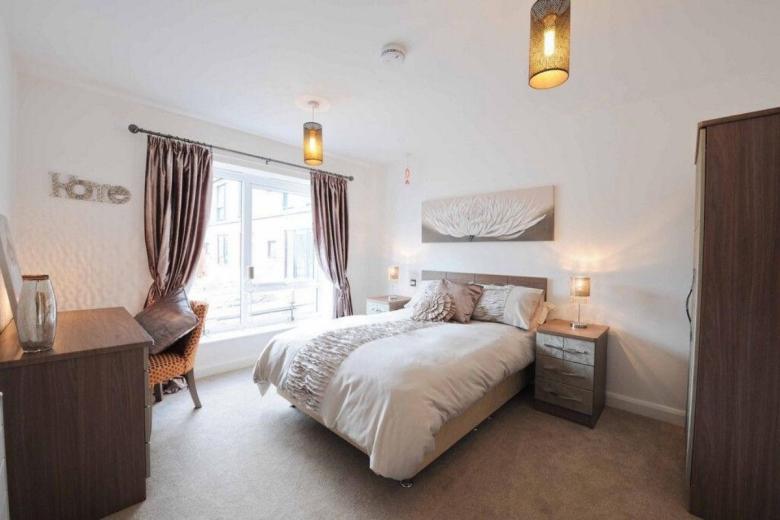 Interior shot of a modern bedroom with a king-sized bed, curtains, and artwork on the walls.