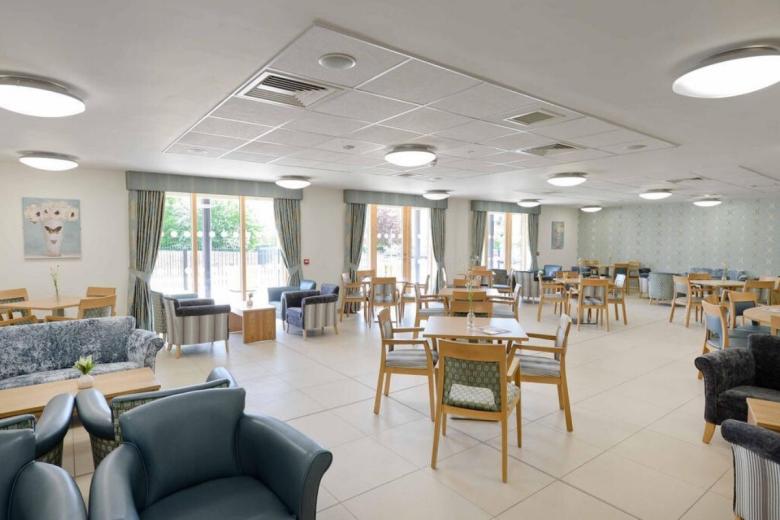 Bright, spacious dining area with light-colored tile flooring and a variety of seating arrangements.