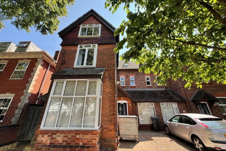 Exterior view of Primrose House, a red brick supported accommodation property with on-site parking.