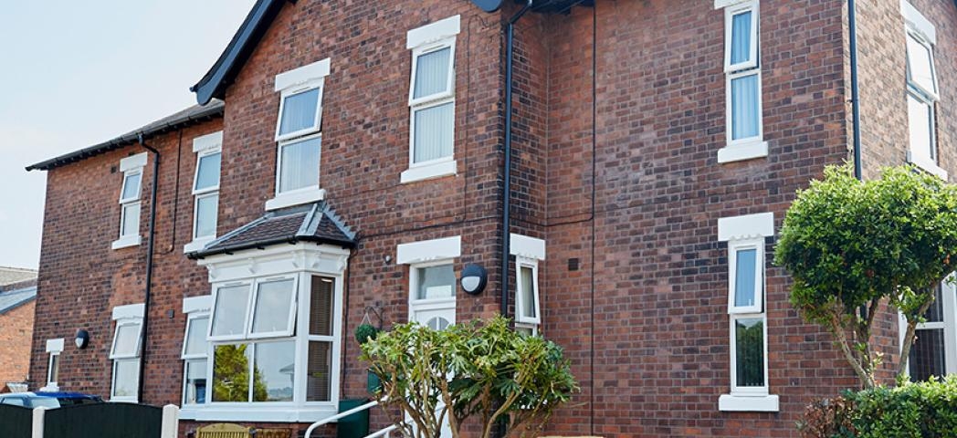 Characteristic, weathered dark brick residential home, with accessible entry to the care facility. 