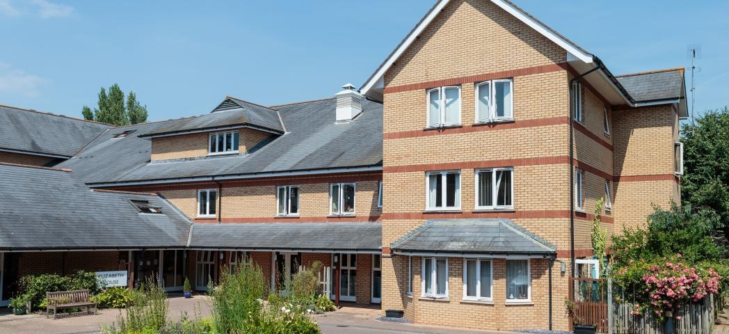 A contemporary red and yellow brick built retirement community property, set across a multi elevation floor plan, set in a well maintained driveway with circular plant feature.