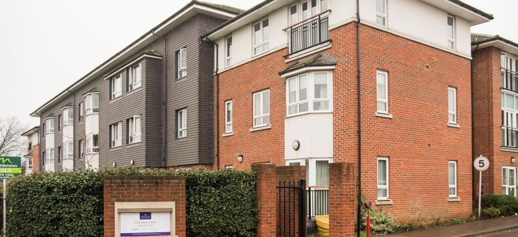 The newly built brick, three storey retirement community. With a large hedge wrapping the front of the property for privacy, an iron gate for pedestrians and a speed restricted driveway.  