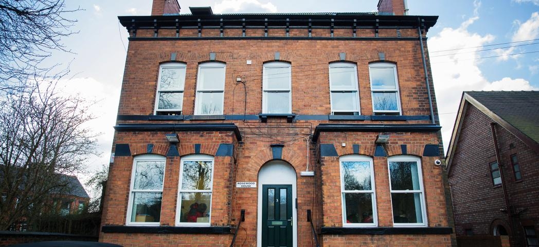 Majestic well weathered brick building, with perfectly symmetrical exterior features including chimneys and windows. As well as a central stepped entry to the front door.