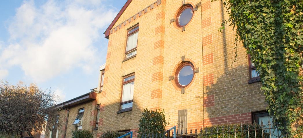 Yellow bricked multi storey supported housing property at John Pounds House in Wandsworth. With a focal feature of circular windows above the entry way.