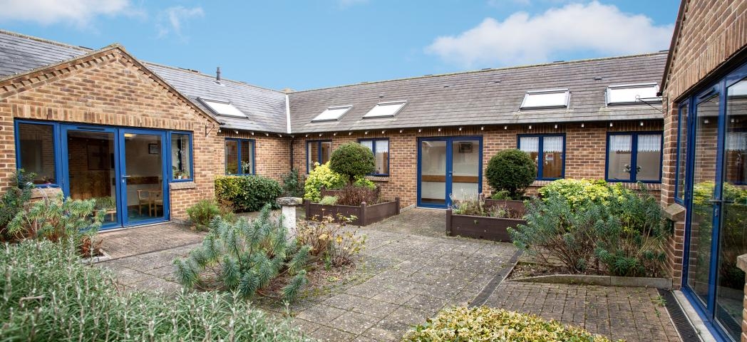 A single storey property, with a small but flourishing courtyard area. The building is built in a 50’s style brown brick built style. The framing for the doors and windows are all in a royal blue adding a pop of colour to the outside area. Skylights have been placed all along the roof.