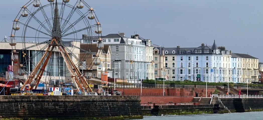 Red and white Ferris wheel located on the pier over looking the beachfront and sea. 