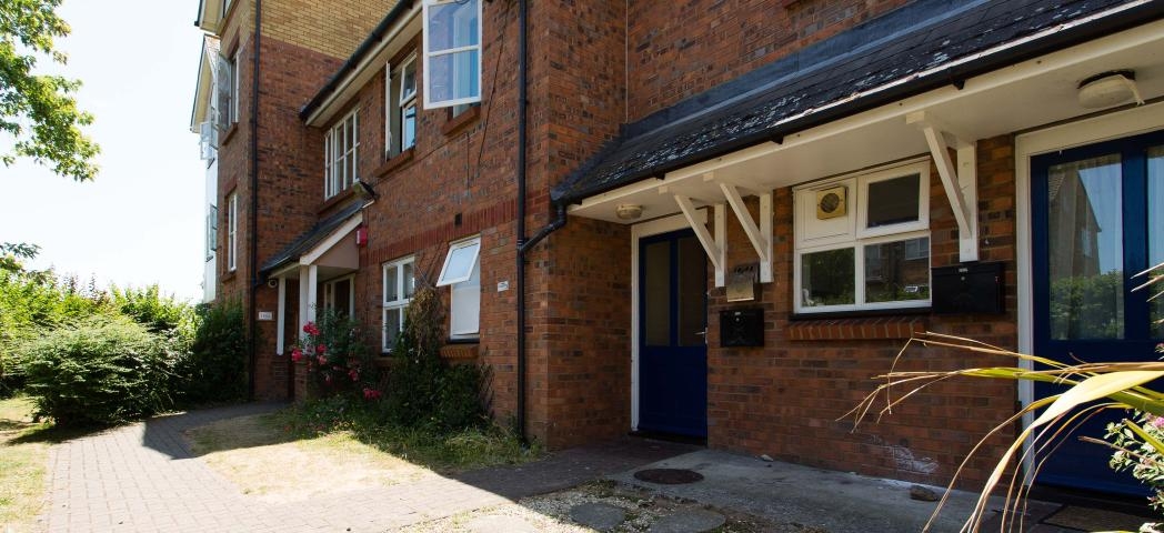 Detached, two storey supported housing property. With scattered windows and centralised blue door and porch.
