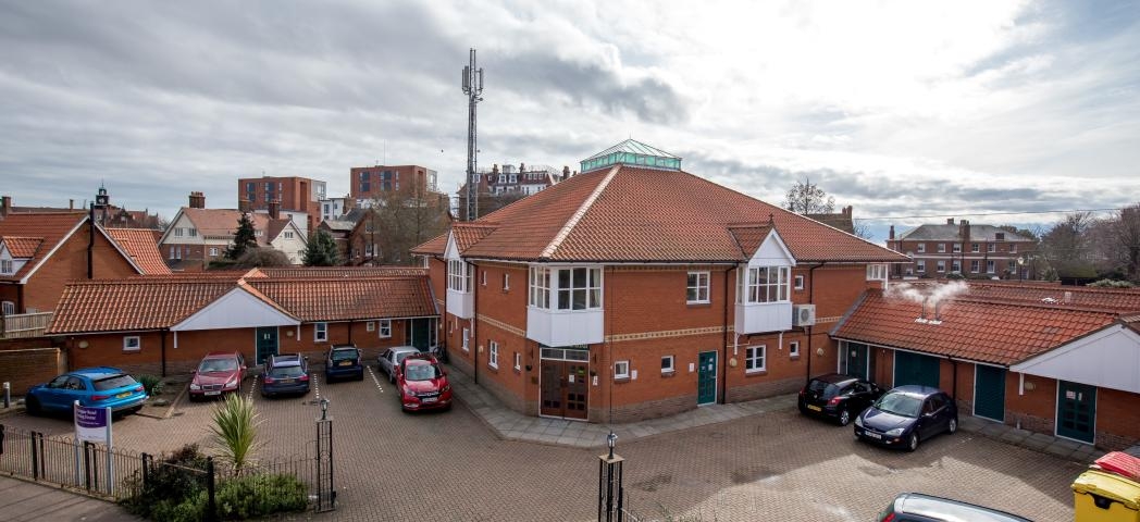 External image of Montague Road Care home, with a car park in front of the large building and high rise buildings in the distance