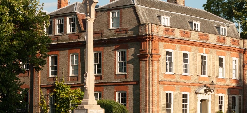 An impressive stone built stepped memorial in front of a yellow and orange bricked stately home in Dedham.